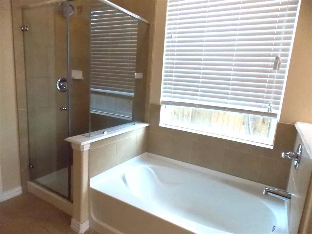 This photo shows a bathroom featuring a white vanity with a single sink and a large mirror. The walls are a neutral color, and there's a doorway leading to another area.