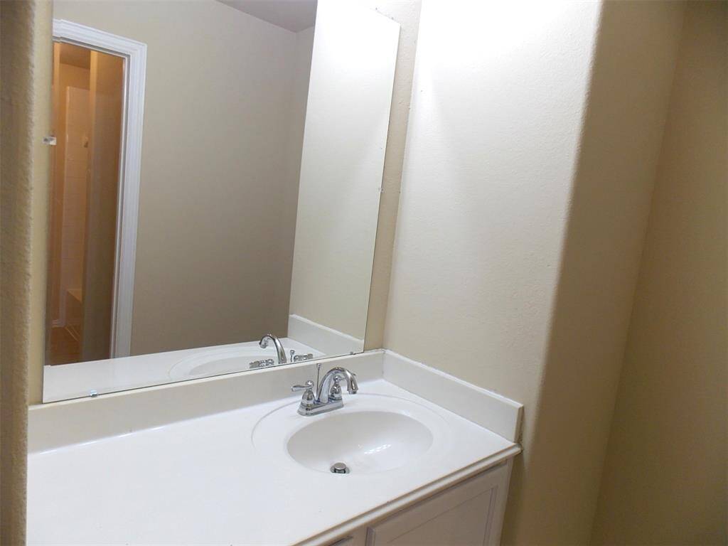 Bright, open room with soft carpet, neutral walls, and a ceiling fan. Features large windows with blinds and a railing overlooking a lower area, creating a spacious feel.