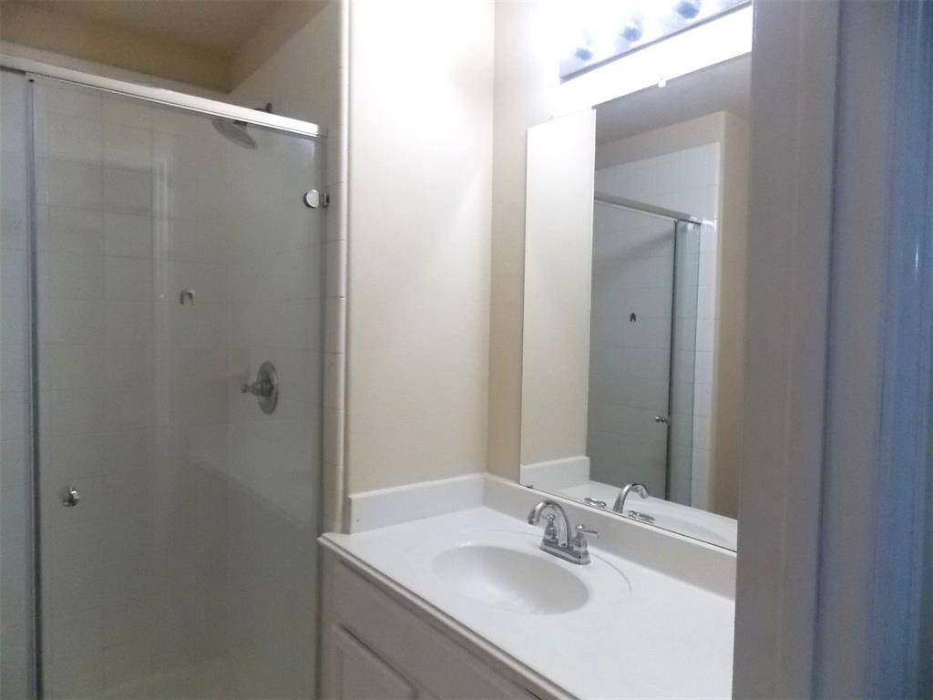 This is a small, carpeted room with neutral walls, featuring a single window with blinds and a ceiling light. There's a door leading to a closet or adjoining space.