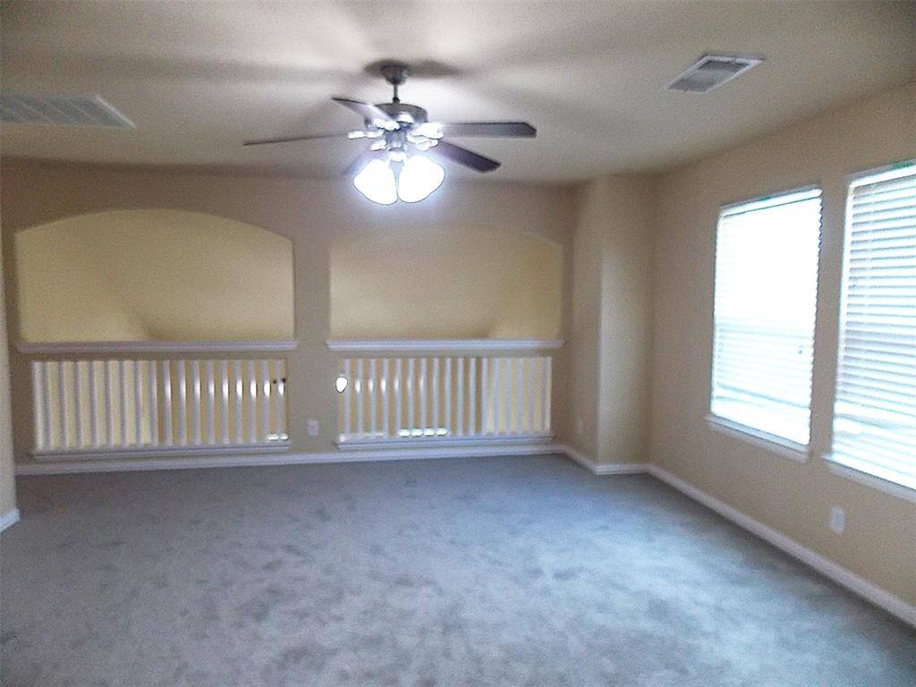This is a small, carpeted room with neutral walls, featuring a window for natural light and a door leading to an adjoining space or closet.