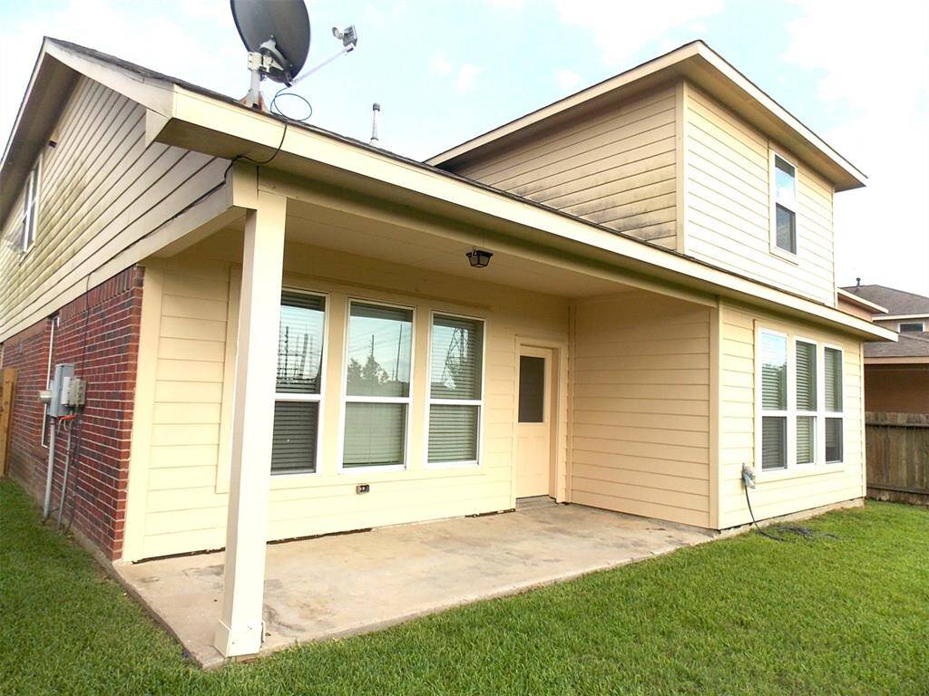 Spacious room with high ceilings, neutral walls, and carpeted flooring. Features a ceiling fan, several windows with blinds, and a door. Ideal for a living area.
