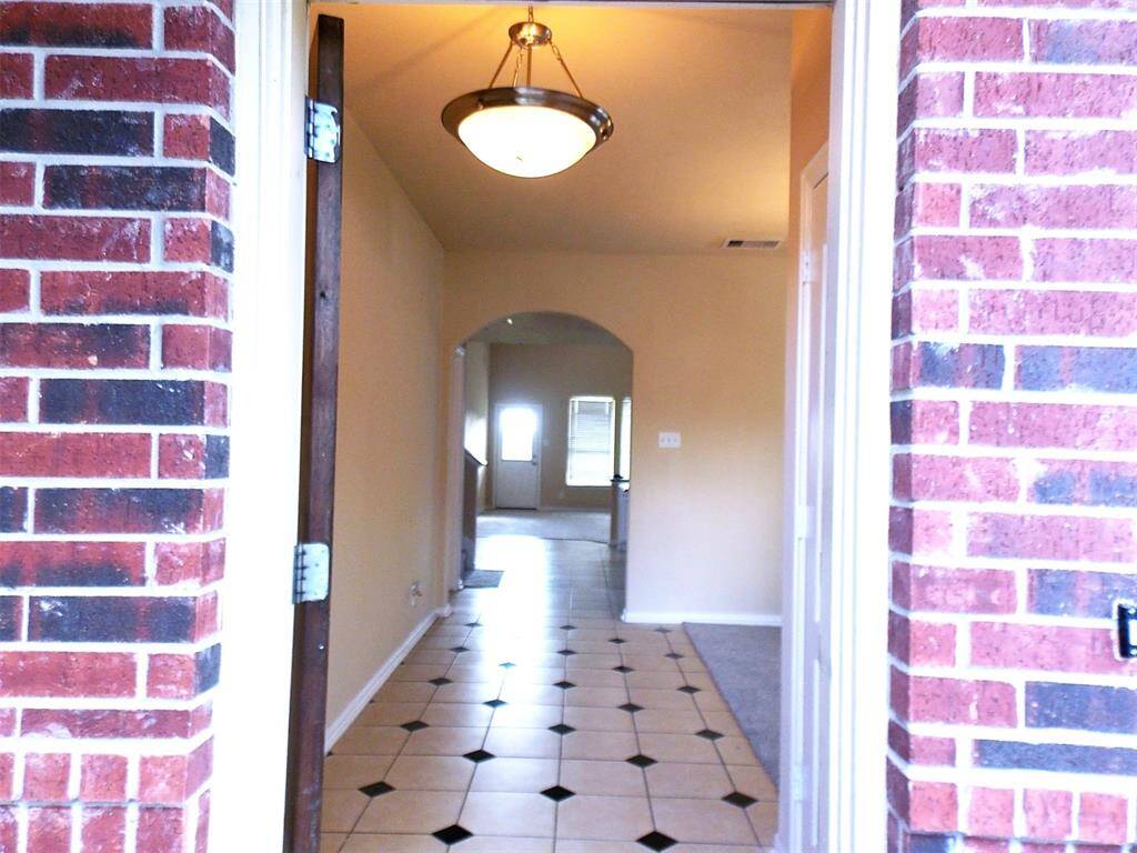 Modern kitchen with granite countertops, white cabinets, and stainless steel appliances. Features a central island, built-in microwave, and a double-door refrigerator. Bright and spacious with tiled flooring.