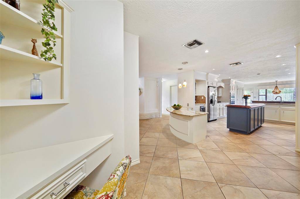This extra large kitchen is full of cabinetry and features granite and solid wood counters, recessed lighting, a wine fridge, SS refrigerator, cooktop, and built-in microwave and oven.