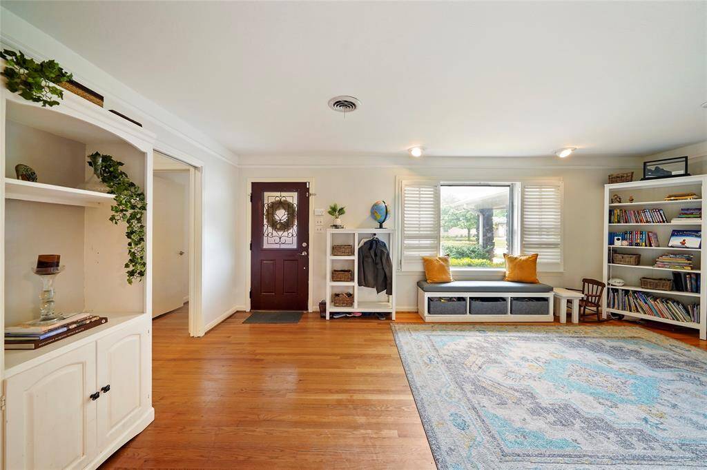 Upon entry, you are greeted by a front room that can function as a formal living, play room, or library with solid wood floors and directional lighting.