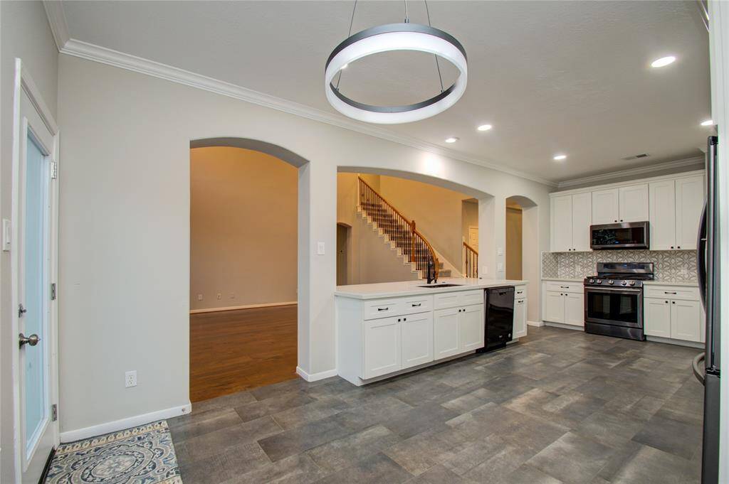 Contemporary pendant light fixture, and a view into an adjacent room with a staircase, adding to its open and inviting feel.
