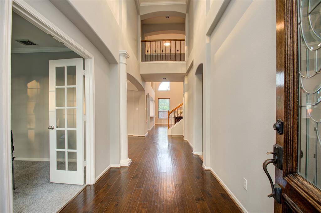 Elegant entry with soaring ceilings and hardwood floors; office with French doors adds sophistication.