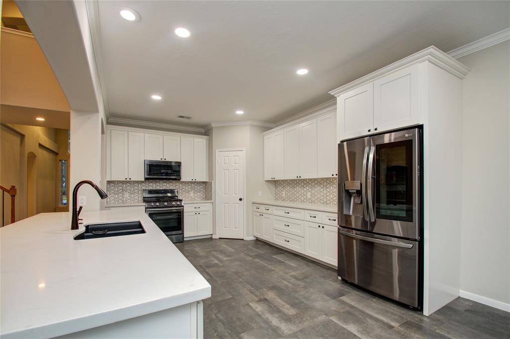Modern kitchen with sleek white cabinetry, stylish backsplash, stainless steel appliances, and a spacious layout.