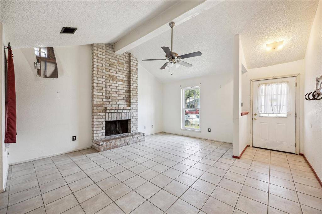 Inviting front door leads into a cozy living room featuring a charming fireplace and an abundance of natural light.