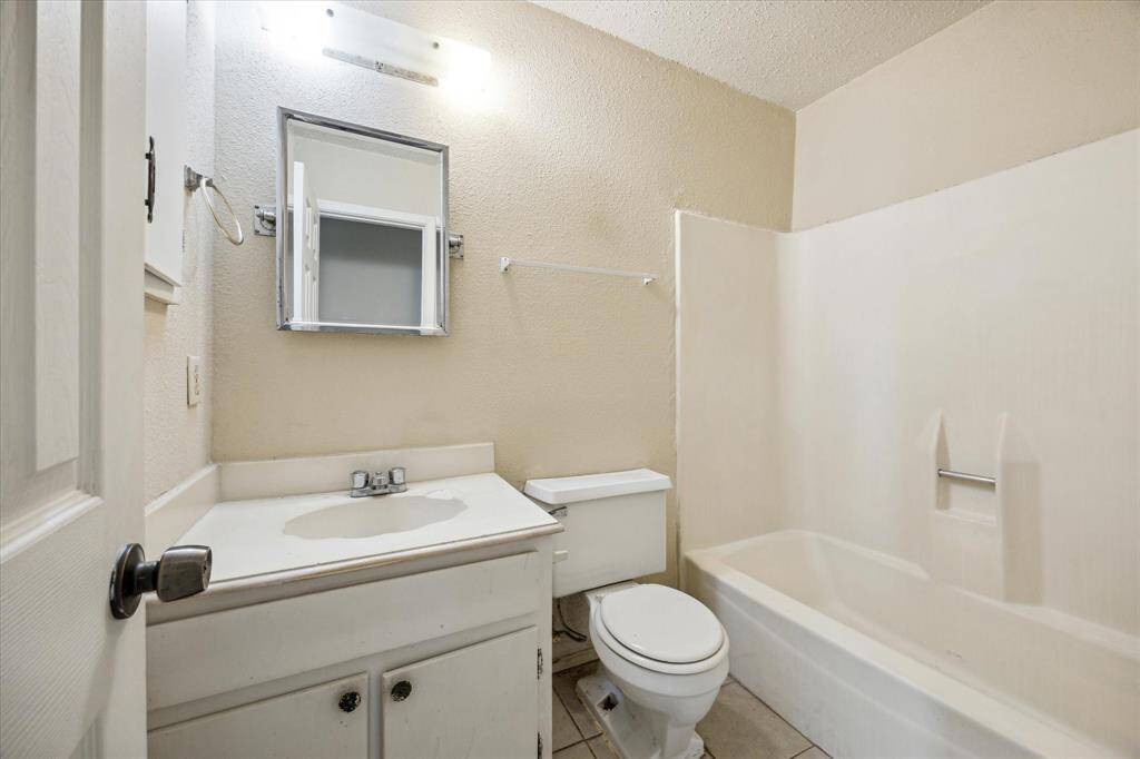 Functional bathroom equipped with a single sink and mirror, along with a practical tub and shower combo for versatile use.