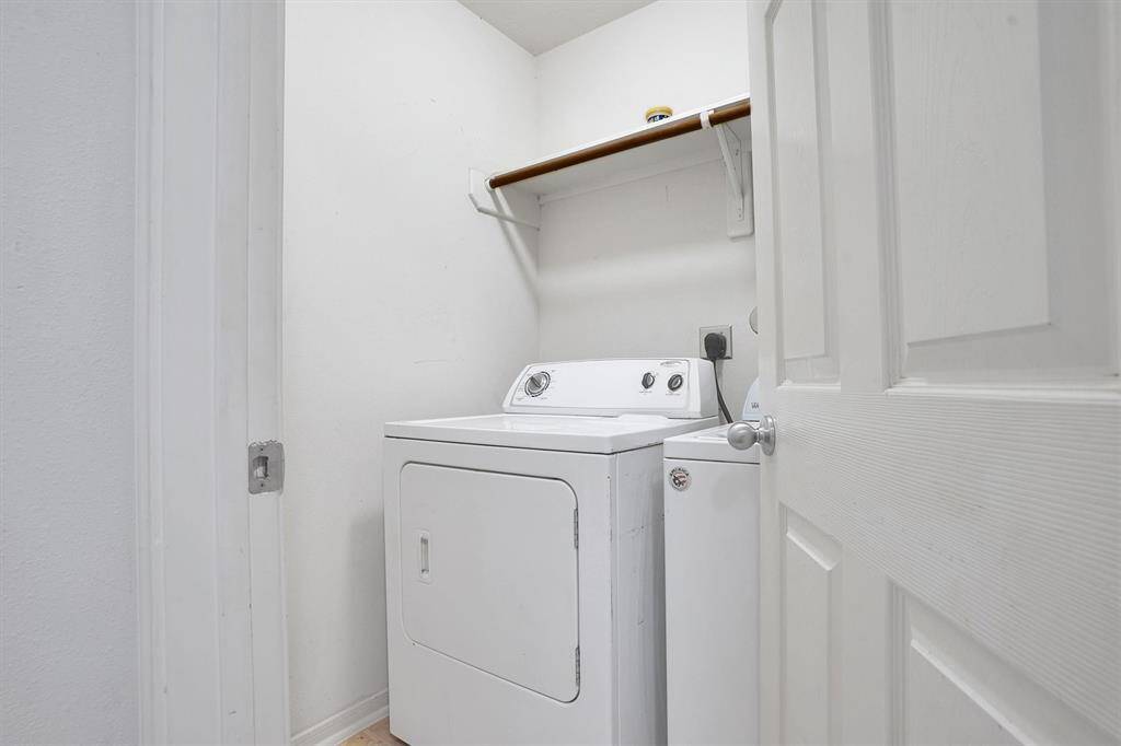 This laundry room features a washer and dryer set, with a shelf above for storage. It's compact and functional, perfect for efficient use of space.