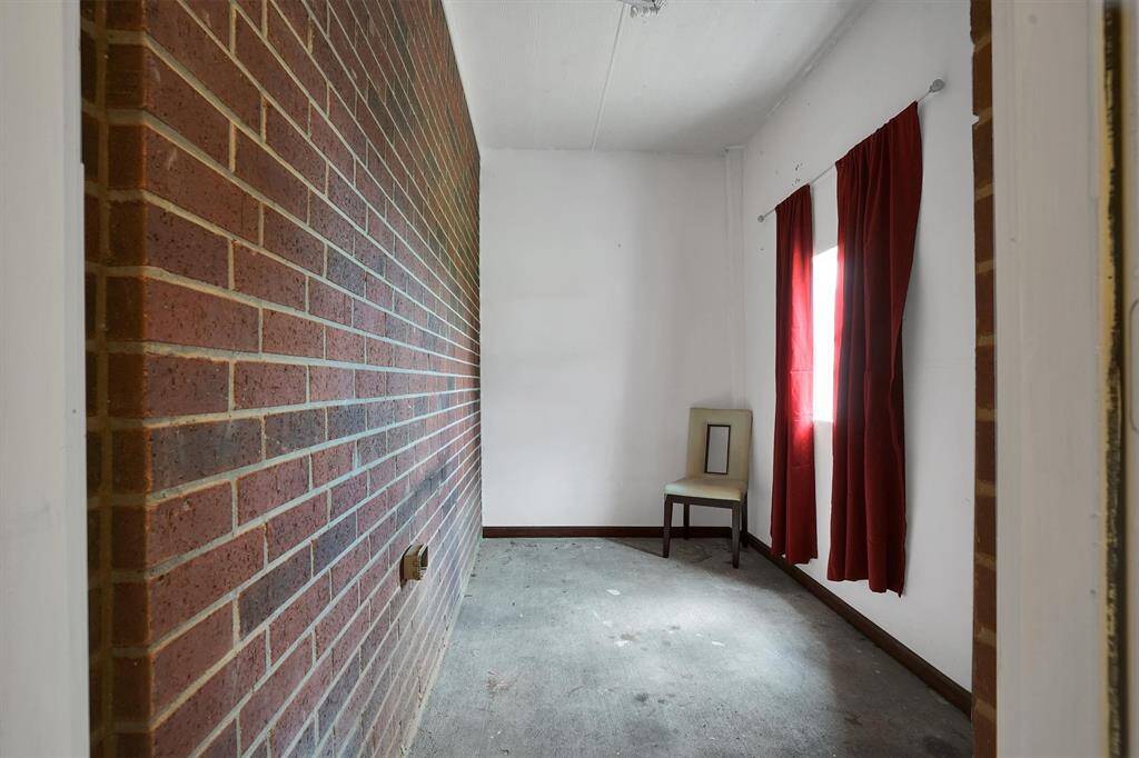 This room features a red brick accent wall and white walls and a small window creating a cozy, minimalistic space.