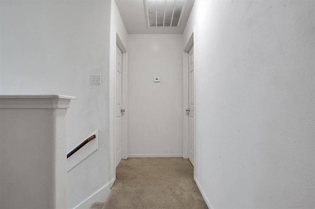 This photo shows a simple, carpeted hallway and a stair railing on the left. It has a clean, neutral appearance, ideal for personalizing.