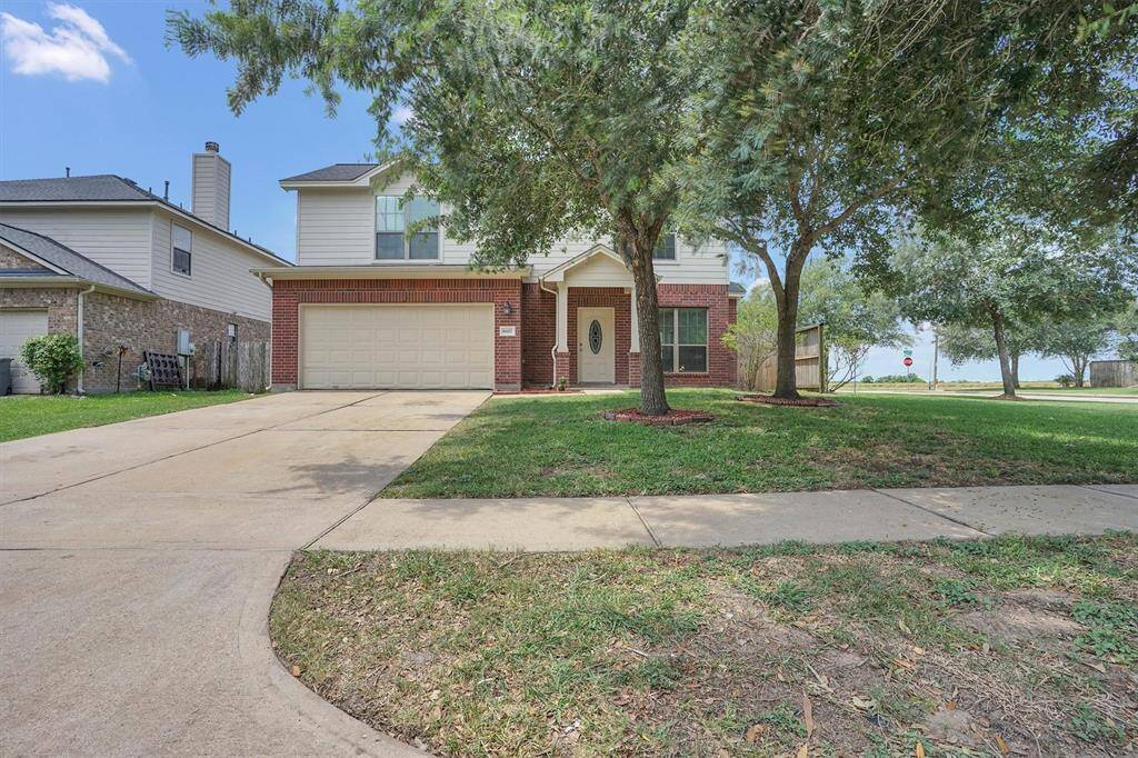 Charming two-story home featuring a brick exterior, attached two-car garage, and a spacious driveway. It is set on a well-maintained lot with mature trees and a lush lawn, situated in a peaceful neighborhood.