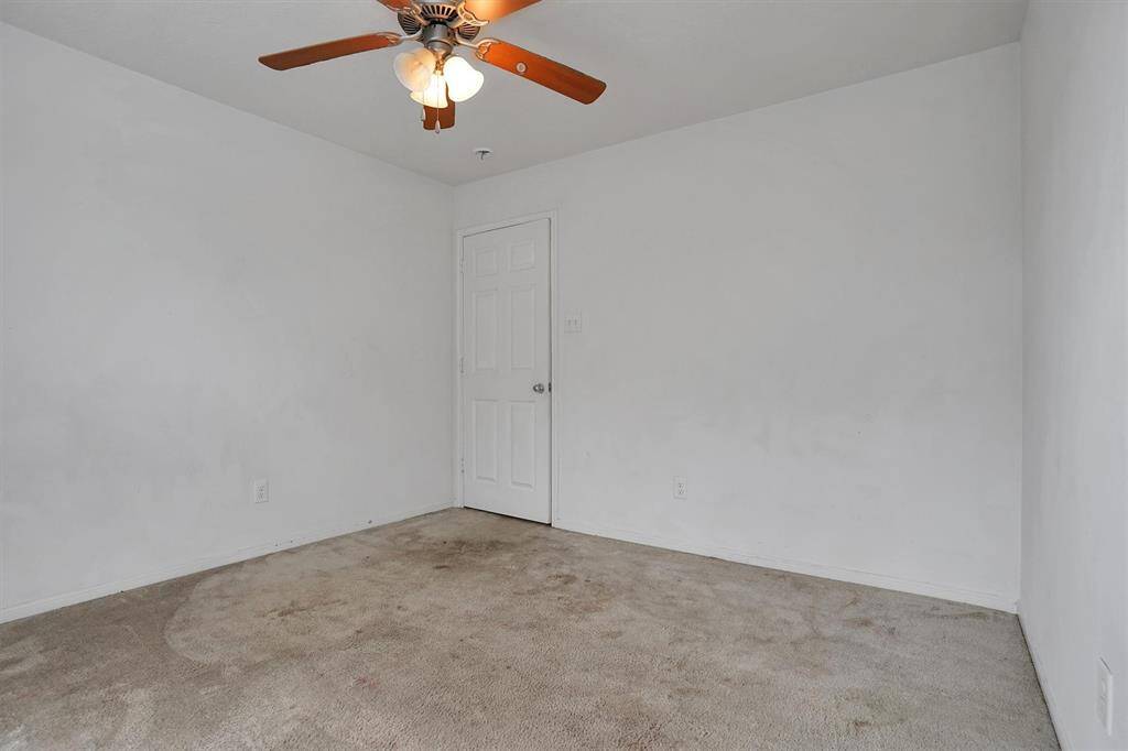 This photo shows a small, empty room with white walls and a beige carpet.The room has a single door, offering a simple, neutral space ready for customization.