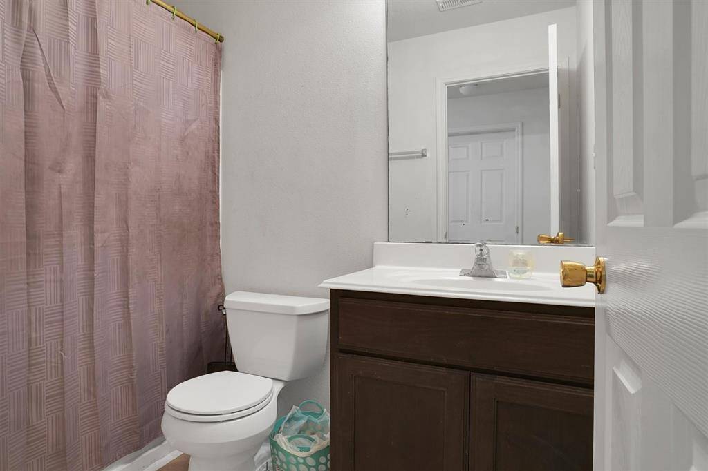 This bathroom features a simple design with a vanity, a toilet, and a shower. The space is compact and functional, ideal for everyday use.
