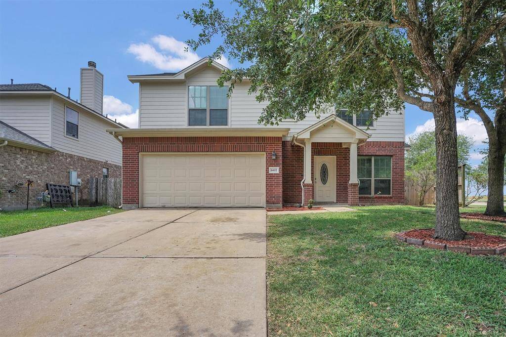 This two-story home features a brick and siding exterior, a two-car garage, and a welcoming front porch. It's set on a spacious lot with a large driveway and mature trees, offering both charm and convenience.
