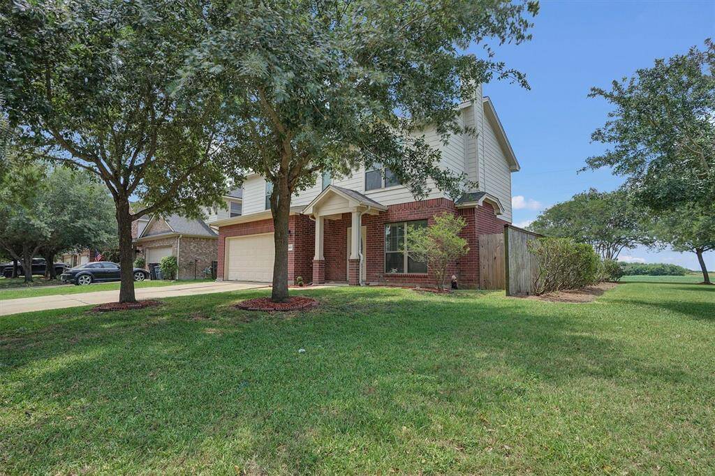 Charming two-story home with a brick and siding exterior, nestled in a spacious, well-maintained yard. Features a two-car garage, mature trees, and a fenced backyard, offering privacy and ample outdoor space.