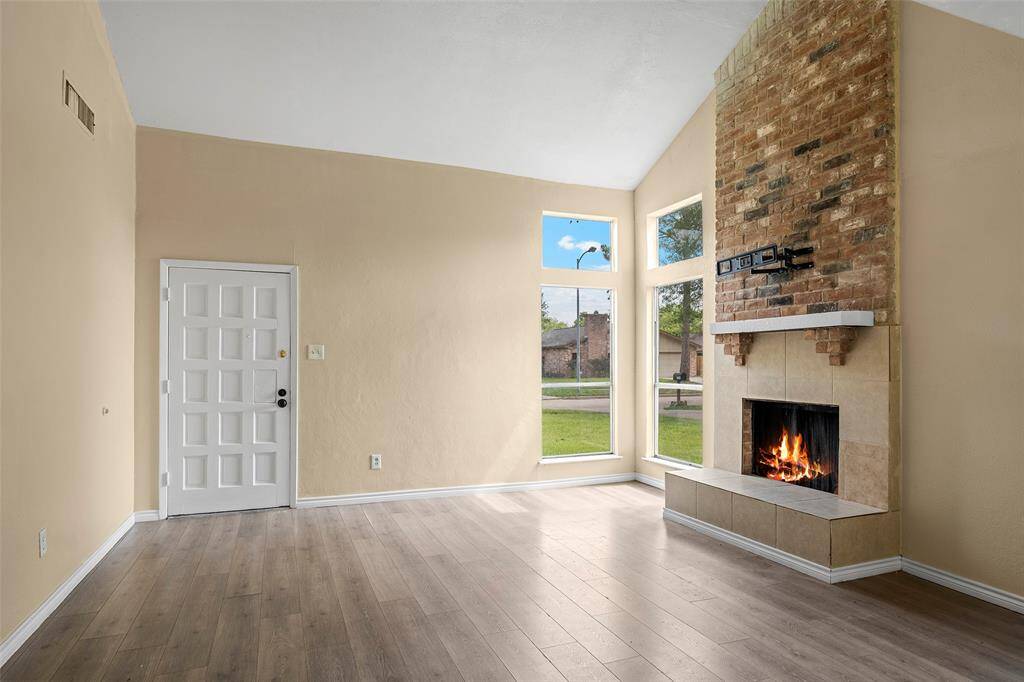 The living room has large windows allowing natural light to fill the space.  The fireplace is accented with brick and a cozy hearth.