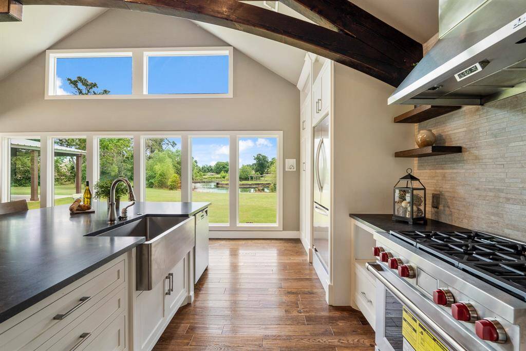 The famous red knobs of the 6-Burner Wolf range with stainless vent hood above is artfully complemented by a hand cut travertine backsplash with tasteful floating shelves. The eye is also drawn to the octet of plate glass windows that flood the space with natural light and breathtaking views.