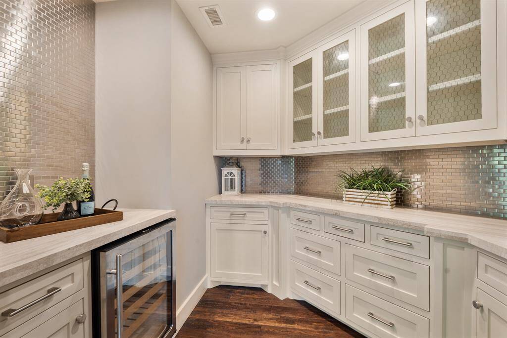 The Wine Room is perfectly located to conveniently serve the Sitting Area, the Dining Room and the Family Room. It artfully blends form and function with beautiful marble counter tops complemented by a designer mirrored backsplash that stretches to the ceiling, an under-counter wine refrigerator and an abundance of cabinet space.