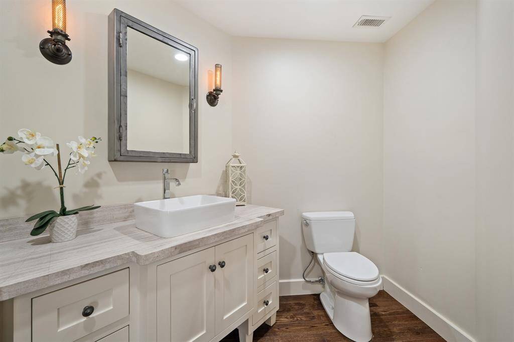 Look at this Powder Room!  Grand in both size and style with a huge vanity with marble counter top with raised porcelain vessel sink and a wall mounted faucet. The ambiance is accentuated by a custom mirror complemented by a pair of antique style sconces.