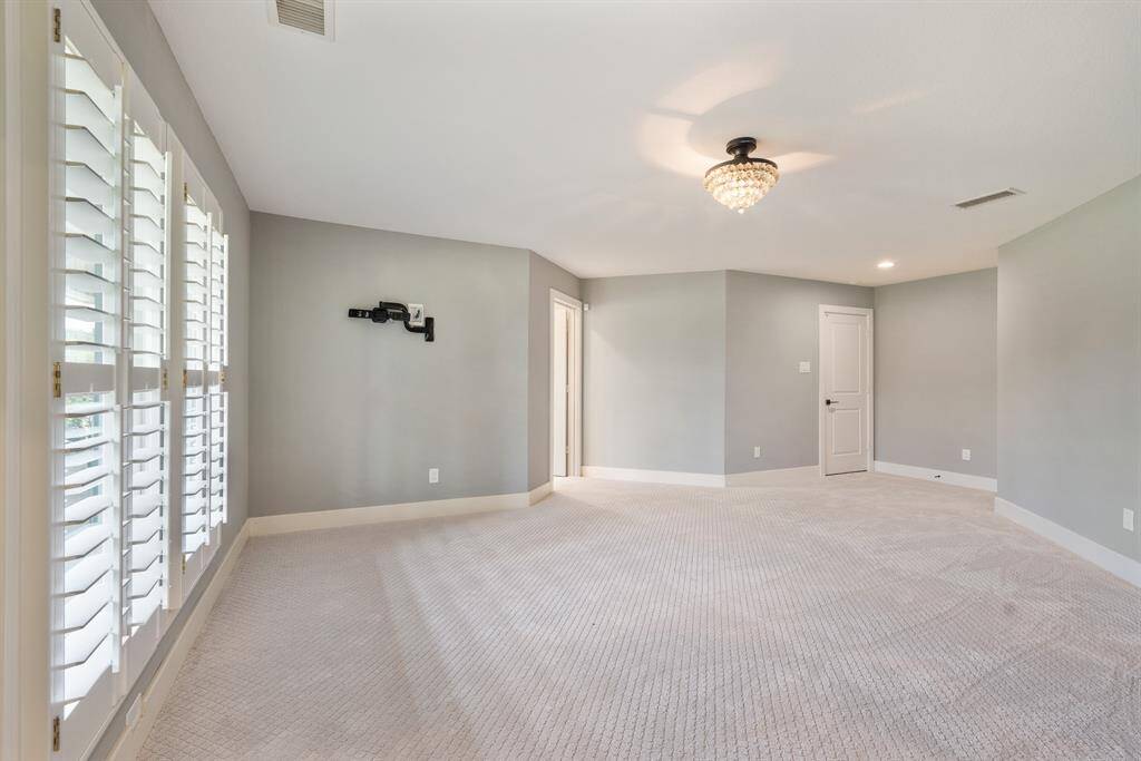 This view of the Primary captures another view of the space, the wall mounted bracket for a TV, the door that opens to the Bath and the door that accesses the room.