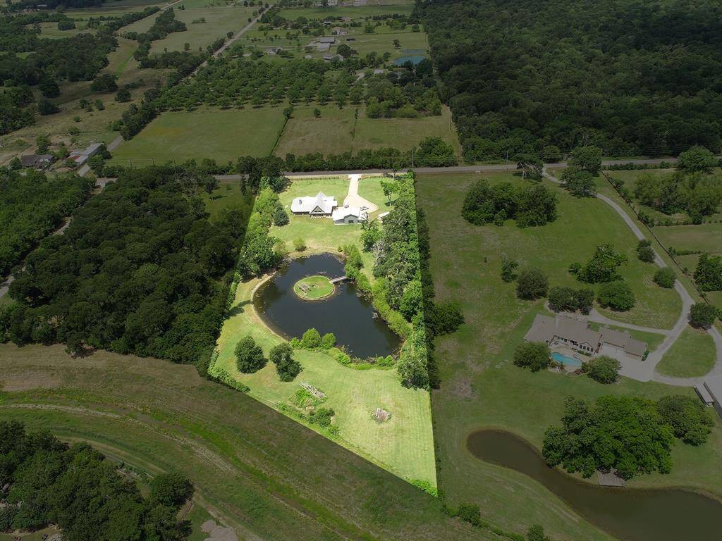 This aerial view looks from the back of the property towards the front that faces Pool Hill Road. It showcases Bessie’s Creek in the foreground and a view of the back of the home and Barn.