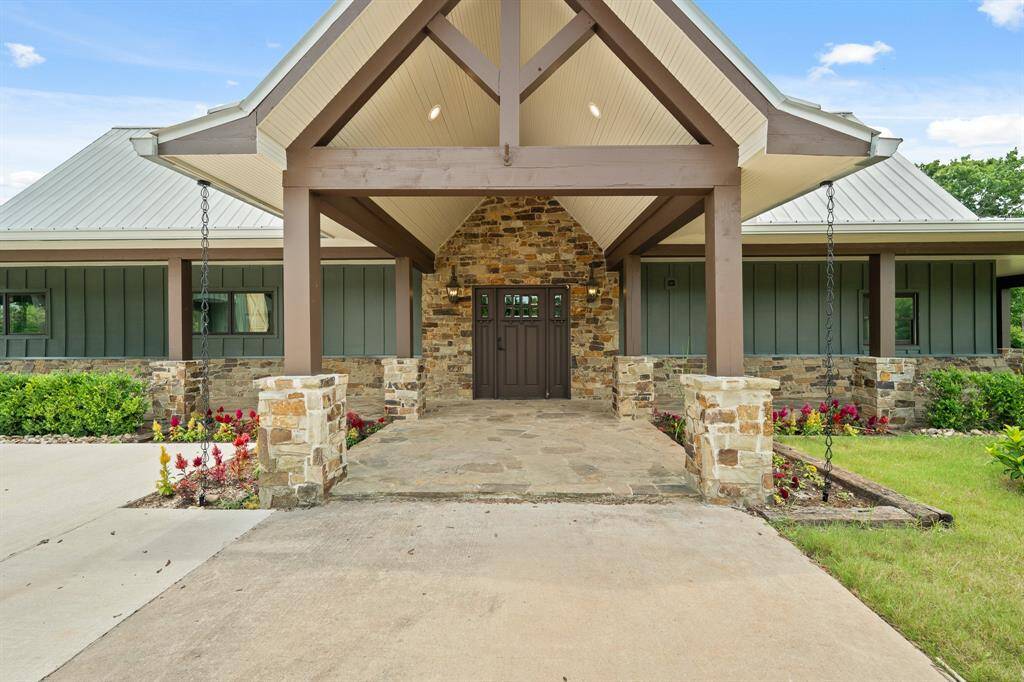 A grand entrance welcomes visitors , with a massive covered Porch with a soaring cathedral ceiling exquisitely finished with an exposed beams, a bead-board ceiling, stone based columns and flagstone walkway.
