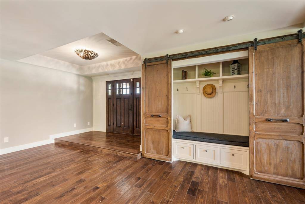 This view captures a look back at the Foyer that has a raised ceiling along with the architecturally designed Mud Room that is tastefully tucked behind attractive barn doors.