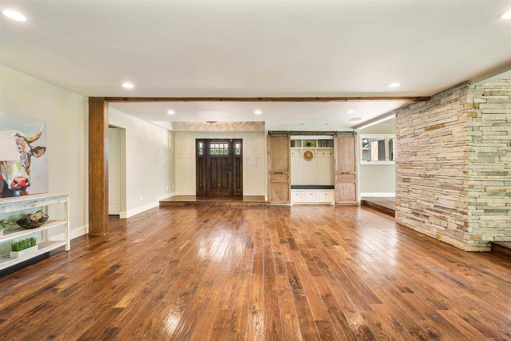The open space design provides flexibility including using this space as welcoming Sitting Area that fronts a beautiful stacked stone wall and a singular beamed ceiling with stained column.