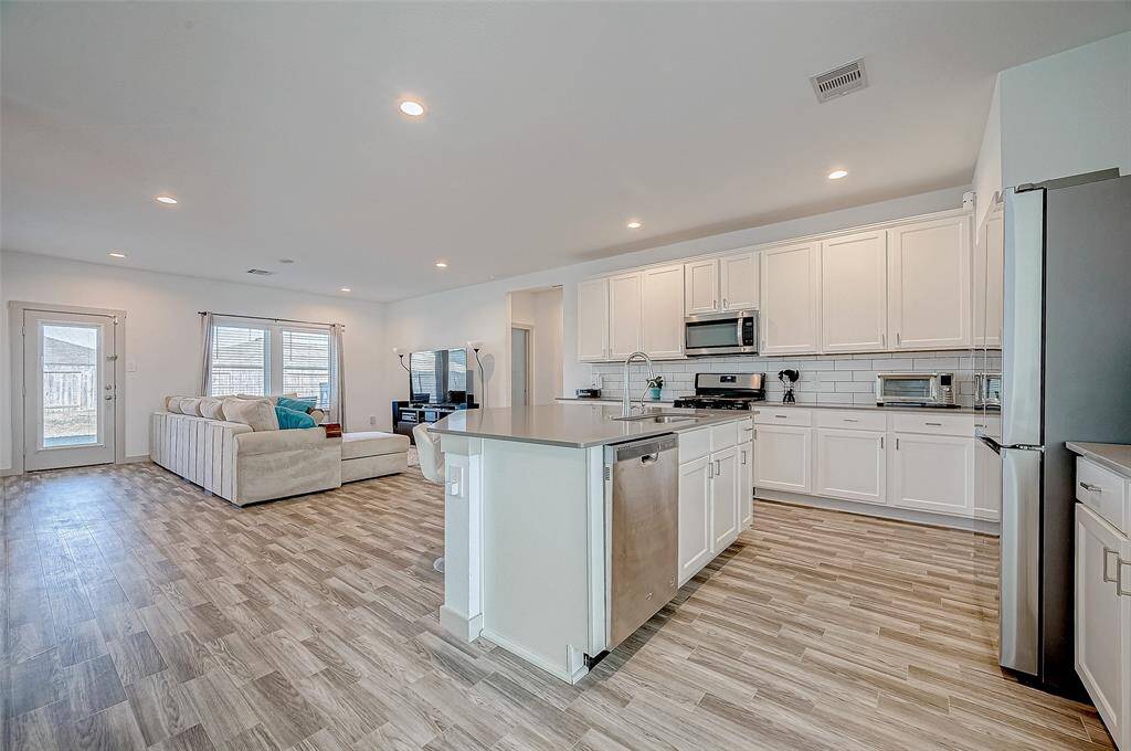 The open layout effortlessly provides ample comfortable seating, while recessed lighting enhances the ambiance of the living room, dining area, and kitchen.