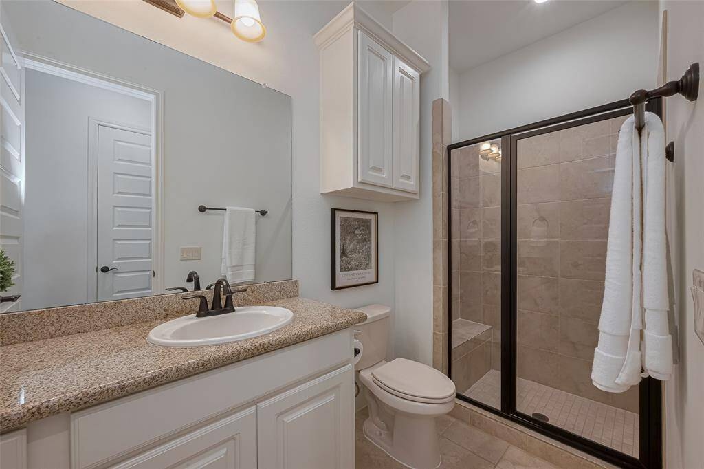 Ensuite bathroom with tile floors, tile shower with bench, oil rubbed bronze hardware, additional built in linen storage above the toilet, granite counters.