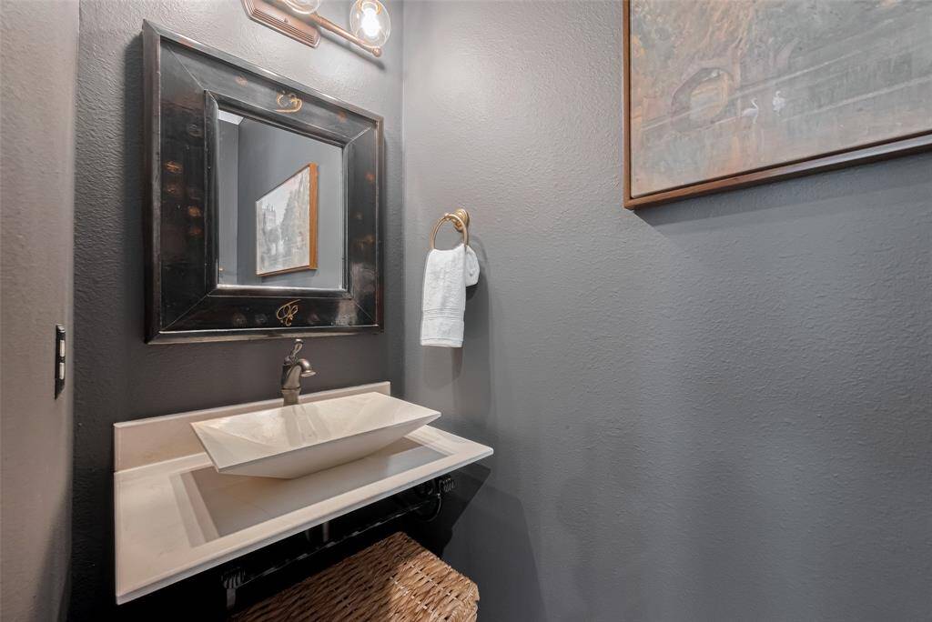 Powder room just off the entry with floating designer styled marble sink, oil rubbed bronze hardware, custom lighting, designer paint, recessed LED lighting, recent tile.