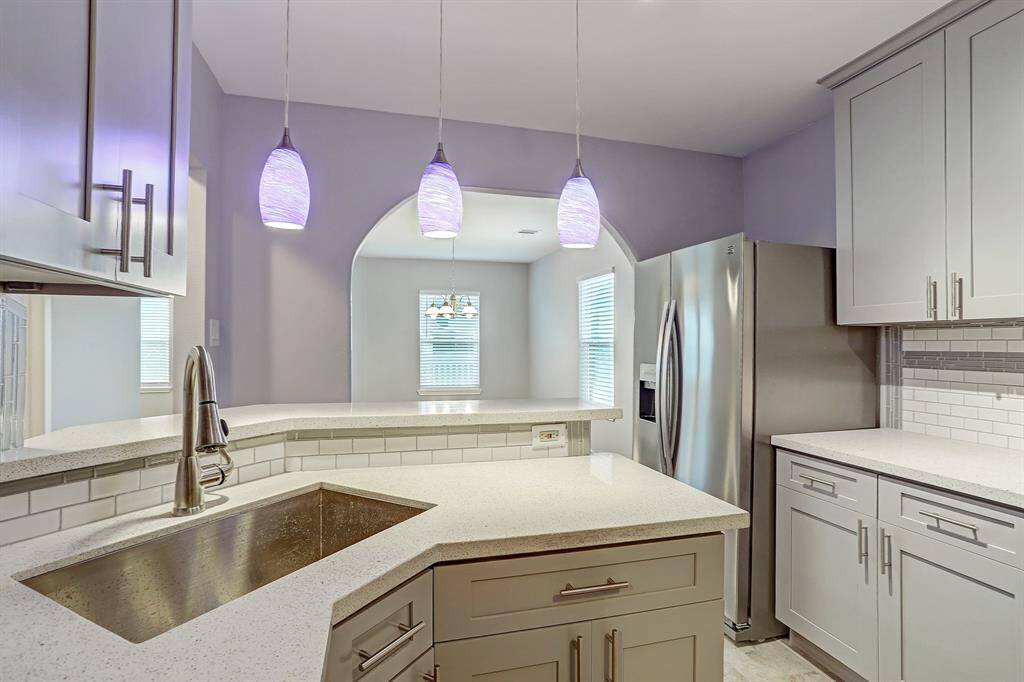 Modern kitchen with stainless steel appliances, white subway tile backsplash, and sleek cabinetry,  with pendant lighting and quartz countertops.