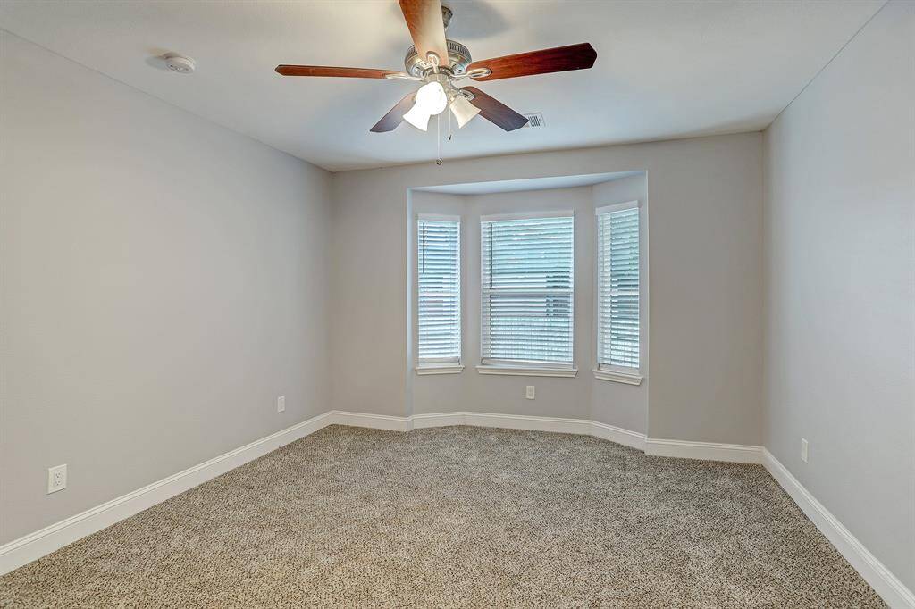 This primary bedroom features carpeting, neutral walls, a ceiling fan with light fixture.