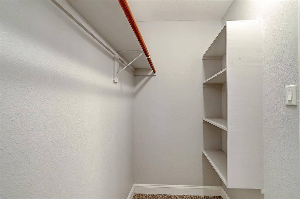 Primary walk-in closet featuring built-in shelves.