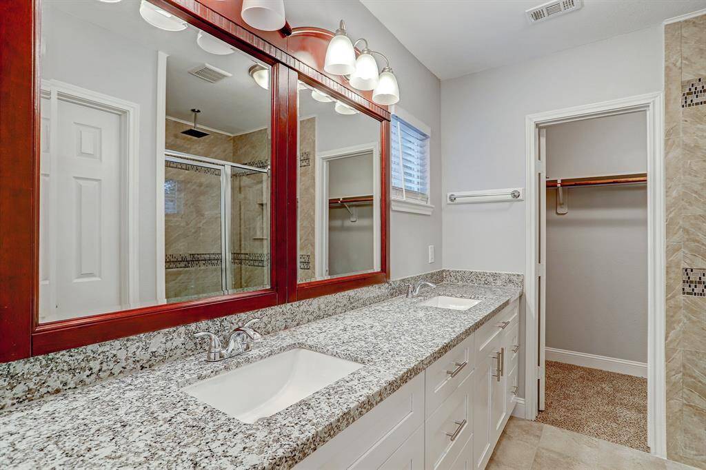 The primary bathroom features a double vanity with quartz countertops, large mirrors, and ample cabinet space.