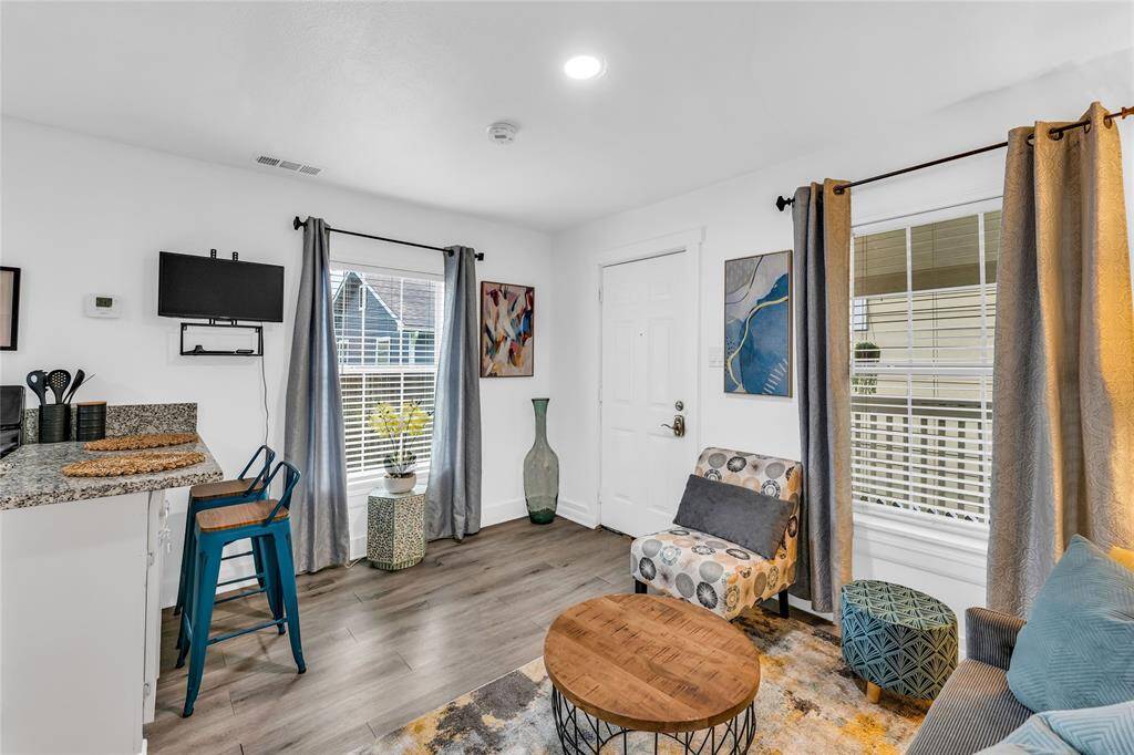 This is a modern, bright, compact space, featuring a kitchenette, a wall-mounted TV, a cozy sitting area.