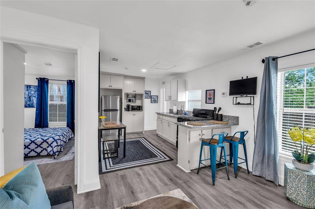 This is a modern, open-plan studio apartment with a breakfast bar, a cozy sleeping area, and a living space that maximizes natural light from the large windows.