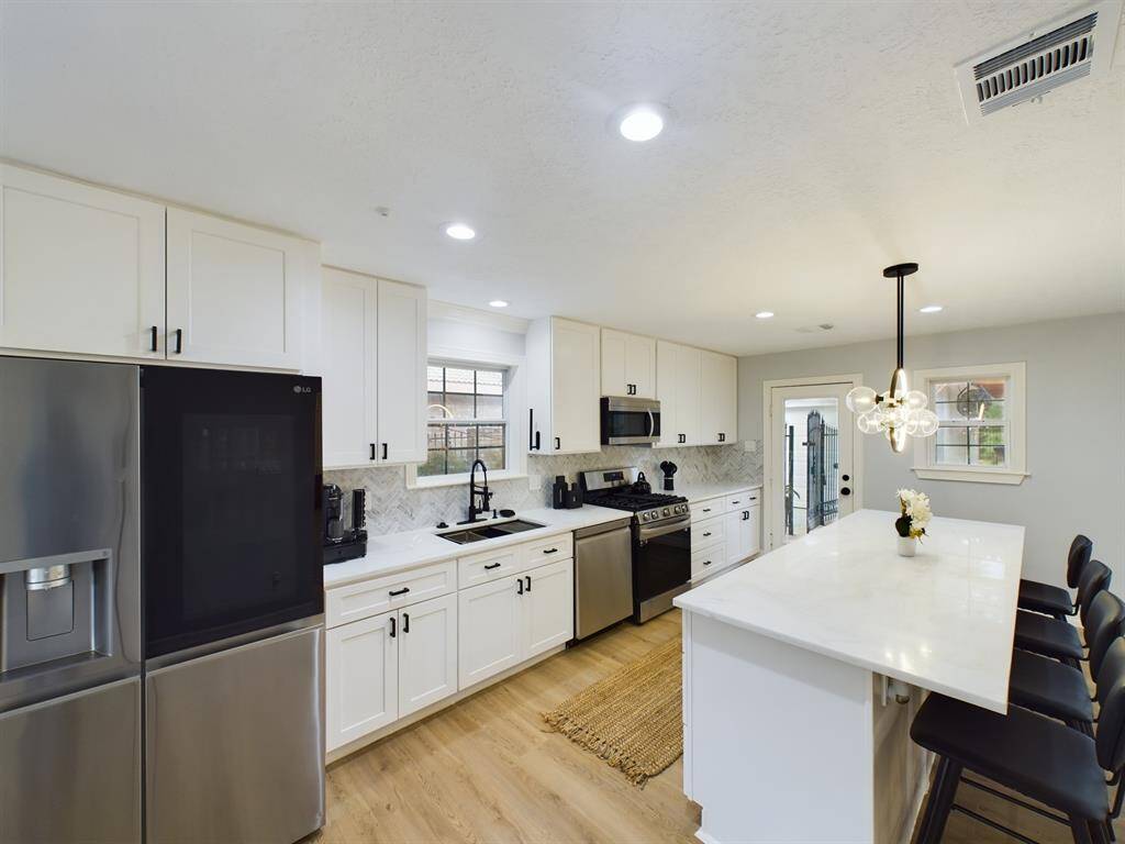 SS Appliances include Quad-Door Refrigerator, Dishwasher, Microwave and Four Burner Gas Range w/Griddle