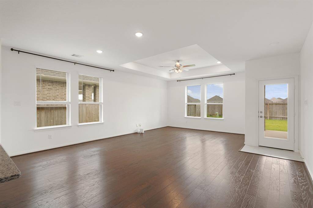 The family room features beautiful engineered hardwood floors that add warmth and elegance to this cozy gathering space.The Family Room features beautiful engineered hardwood floors, a stunning trey ceiling with a ceiling fan and large windows that flood the space with natural light.