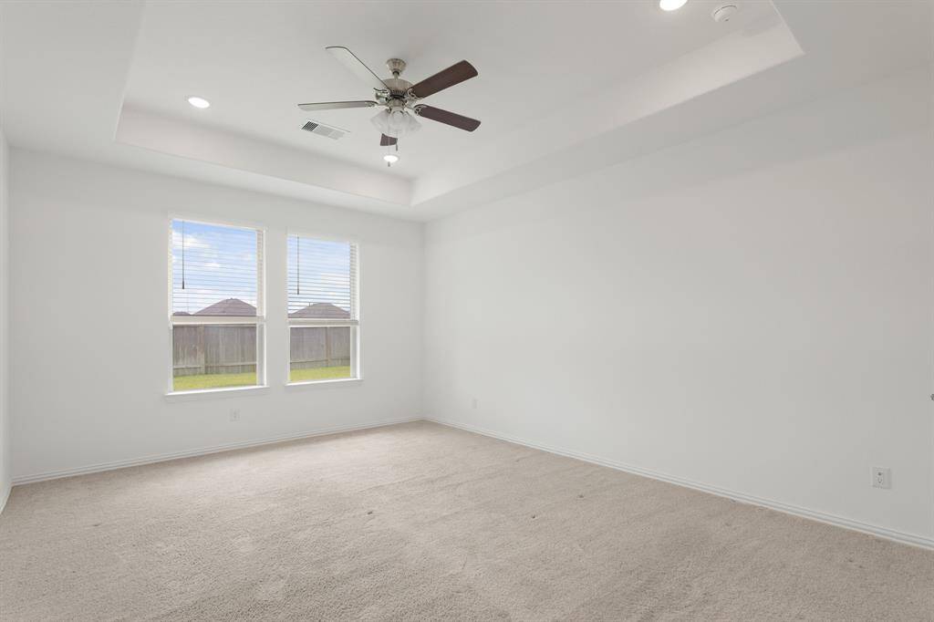 The Primary Bedroom windows offer tranquil views overlooking the spacious backyard, bringing natural beauty indoors. Window blinds installed throughout the home provide a clean, modern look and enhanced privacy.