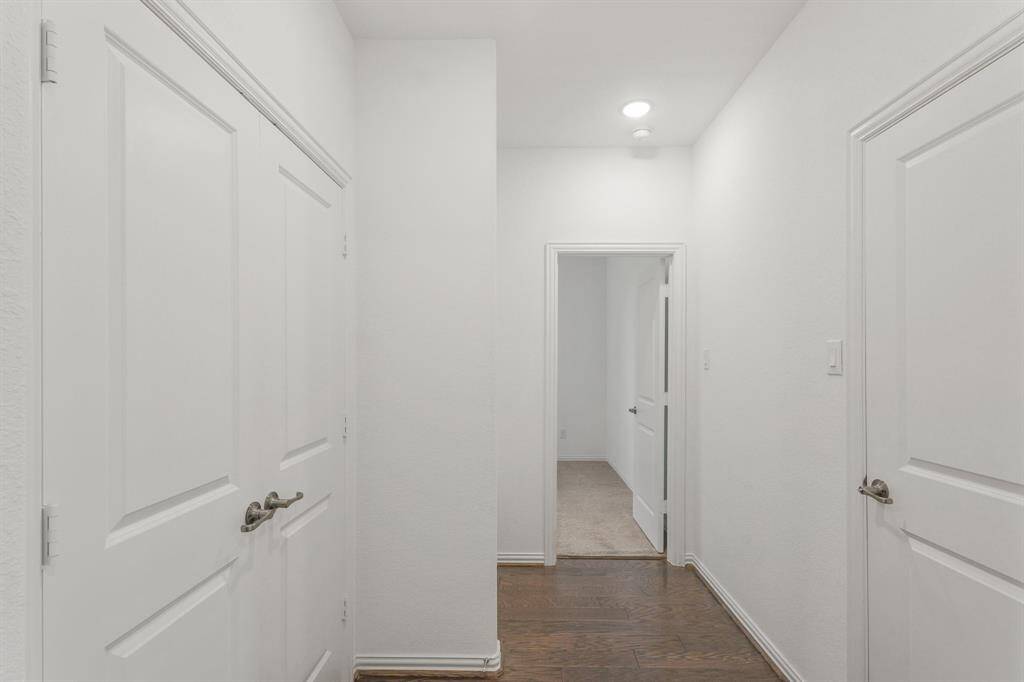 Central Hallway with crisp white walls, hardwood flooring, and recessed ceiling light provide a fresh, open feel leading to adjacent rooms and closets.