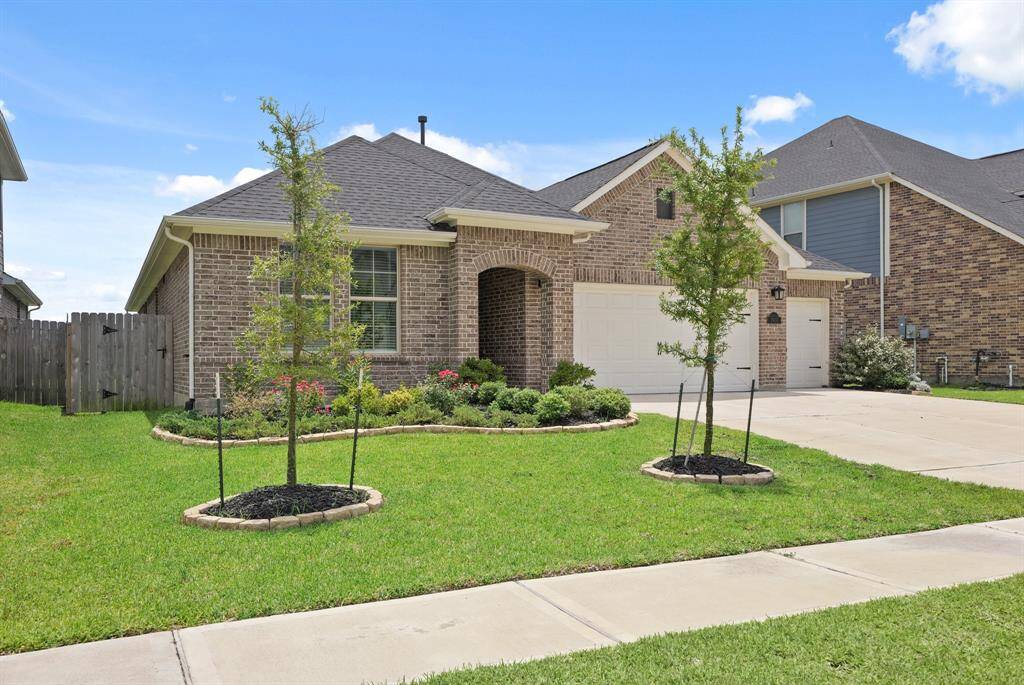 The beautiful front exterior is framed by lush landscaping and a vibrant flower bed that adds charming curb appeal.