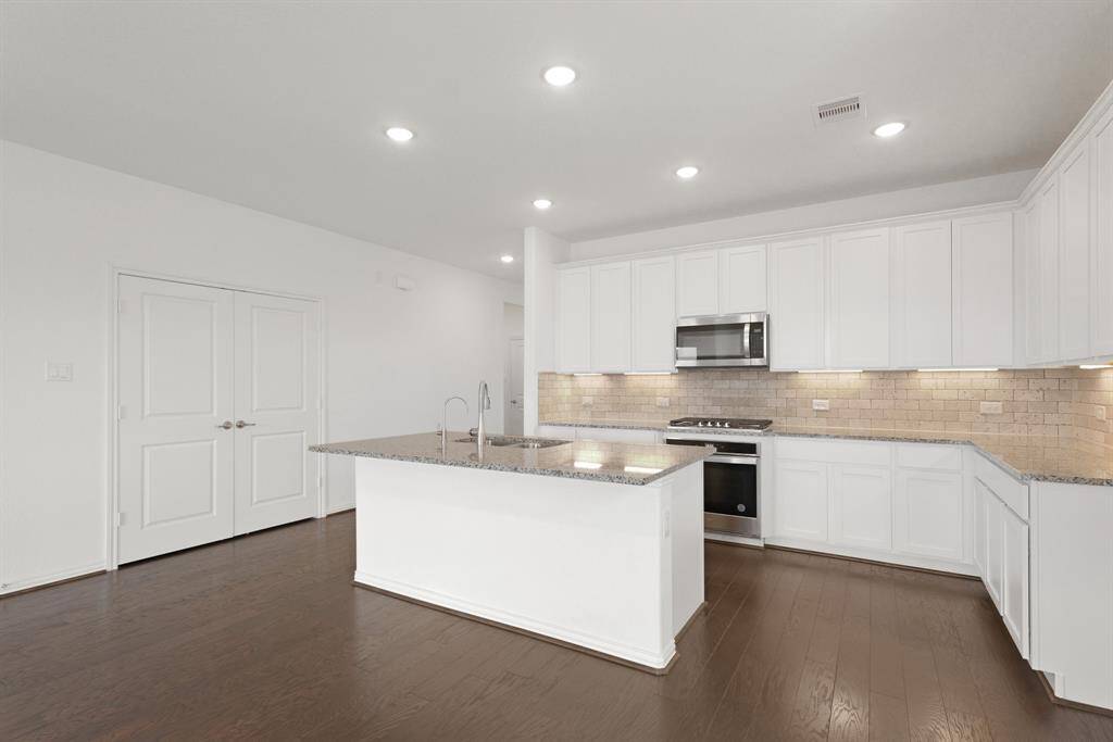 Recessed ceiling lights brighten the entire Kitchen, highlighting the elegant cabinetry and gleaming countertops.