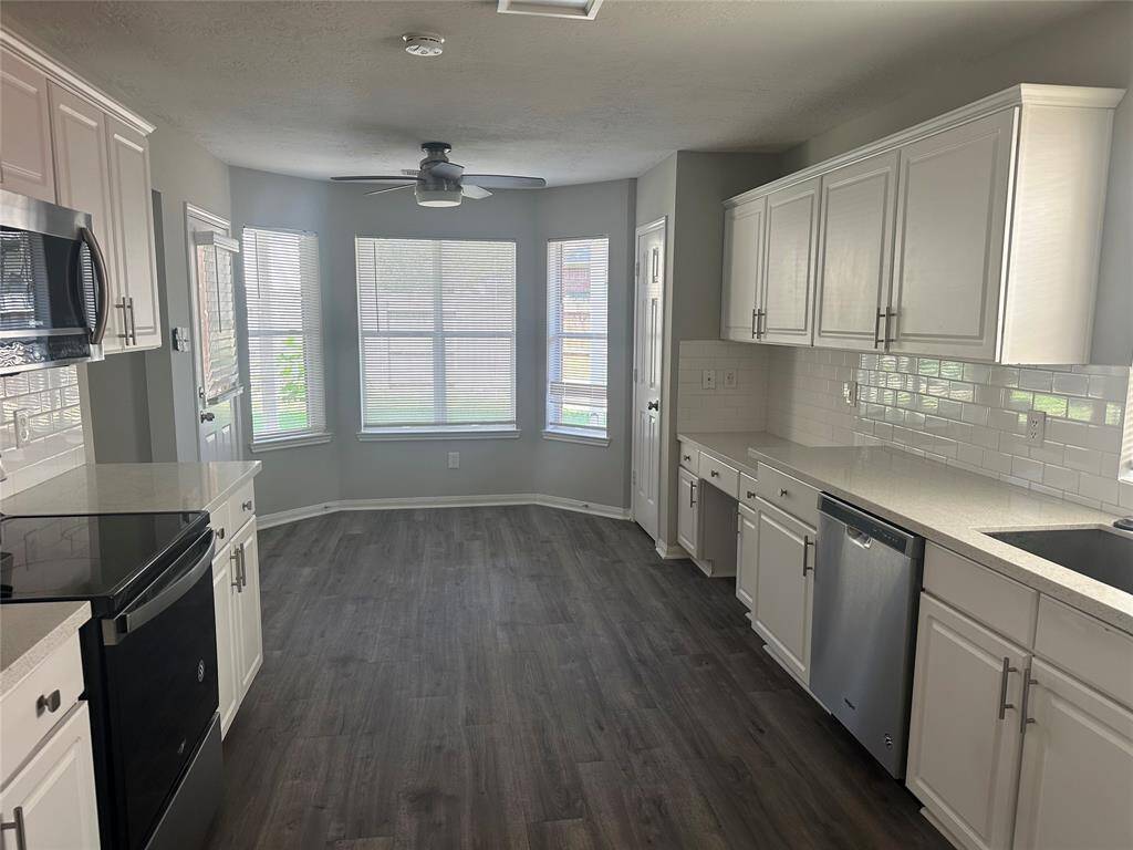 Galley kitchen has been updated with white cabinets, subway tile backsplash and gray/white solid surface countertops.
