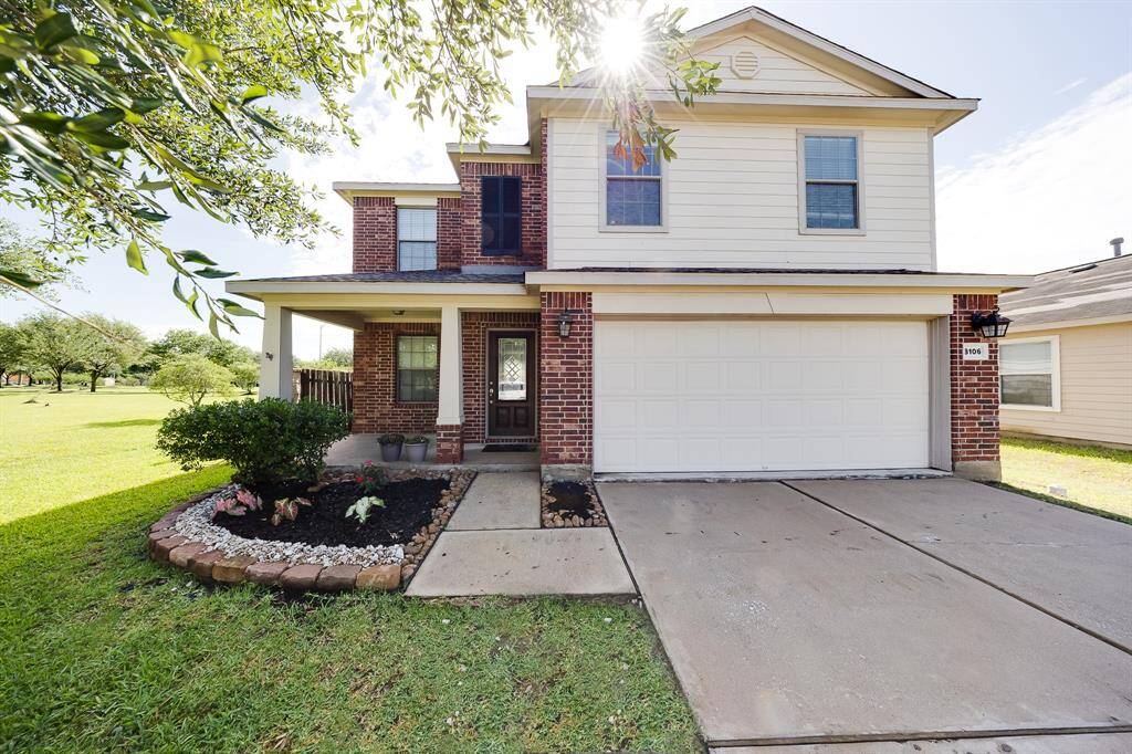 Charming two-story home with brick and siding exterior, lush landscaping, and a welcoming covered front porch.