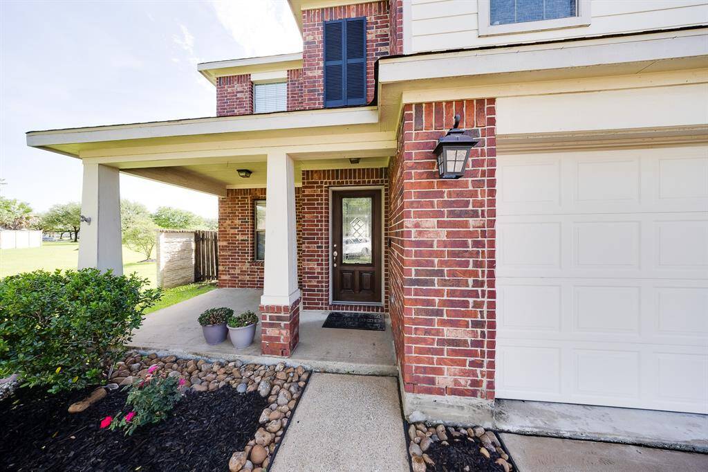 Inviting front entryway with decorative brickwork, updated light fixture, and detailed landscaping for extra curb appeal.