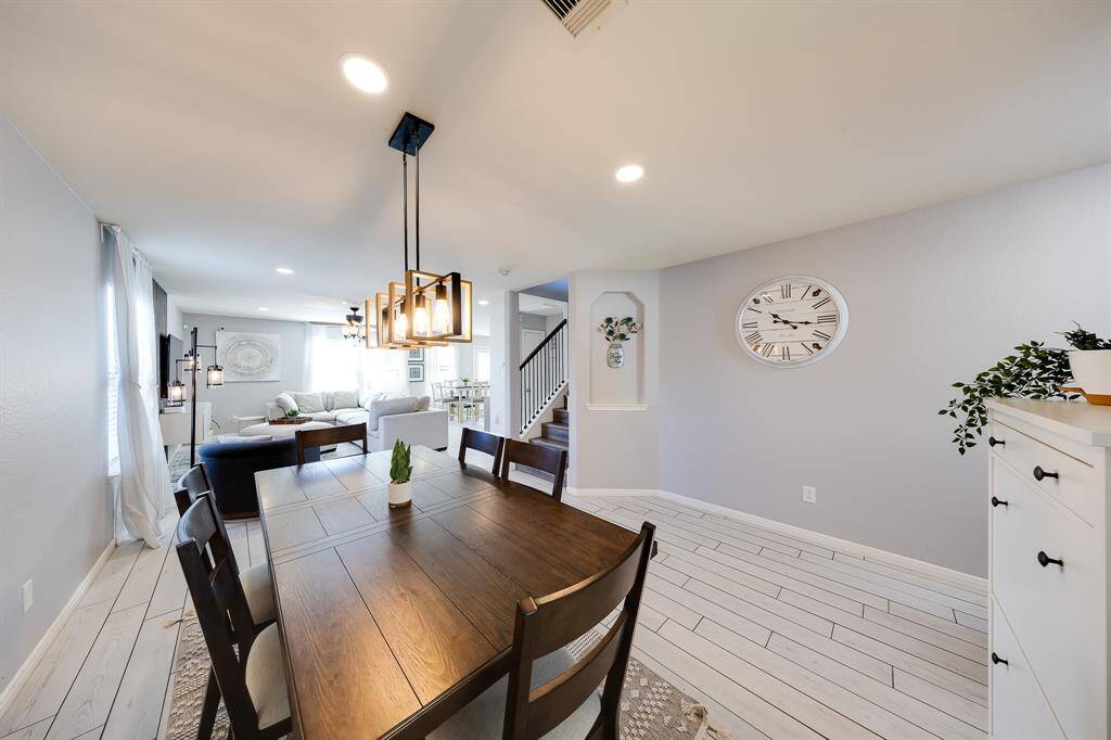 Elegant dining area with modern chandelier, natural light, and easy access to the living room and kitchen.