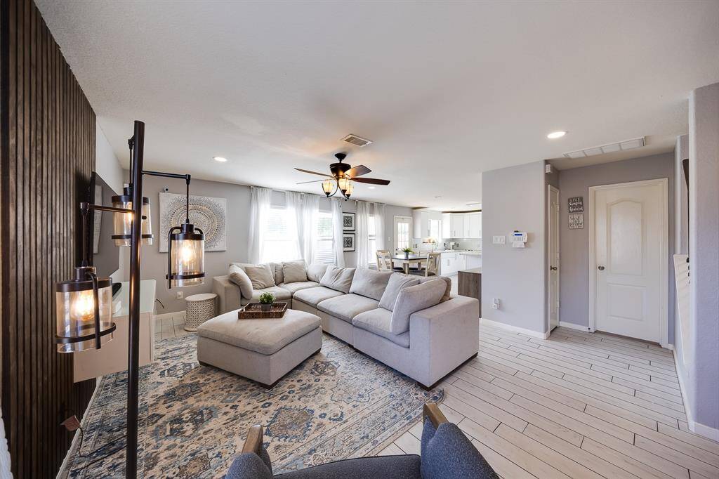Inviting open living area with soft natural light, cozy sectional, and a view into the stylish kitchen.